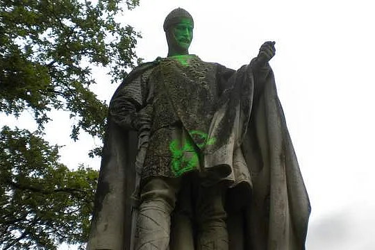 Denkmalfigur mit grüner Farbe vor der Reinigung